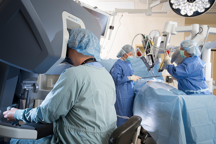 A surgeon using a robotic assistant to perform surgery on a patient.